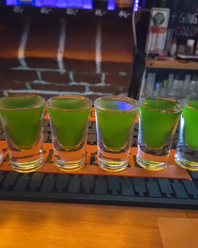 Rząd zielonych shotów na pomarańczowej macie barowej